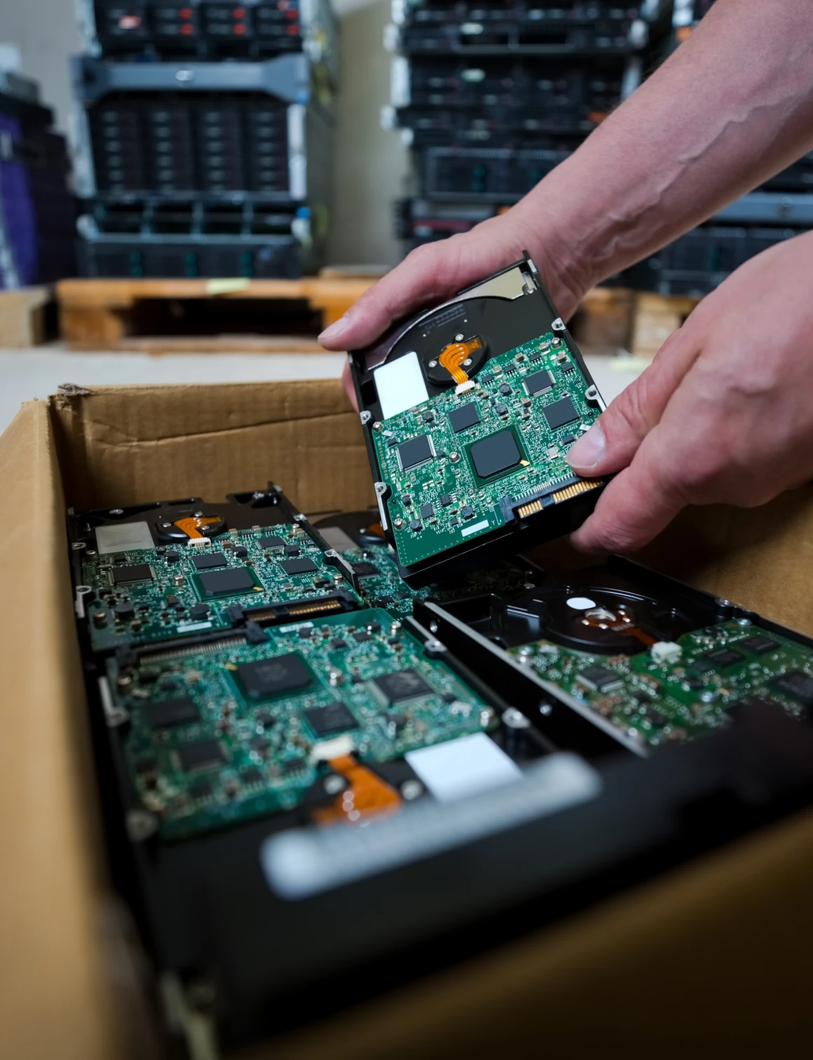 Hands sorting computer hard drives in box.