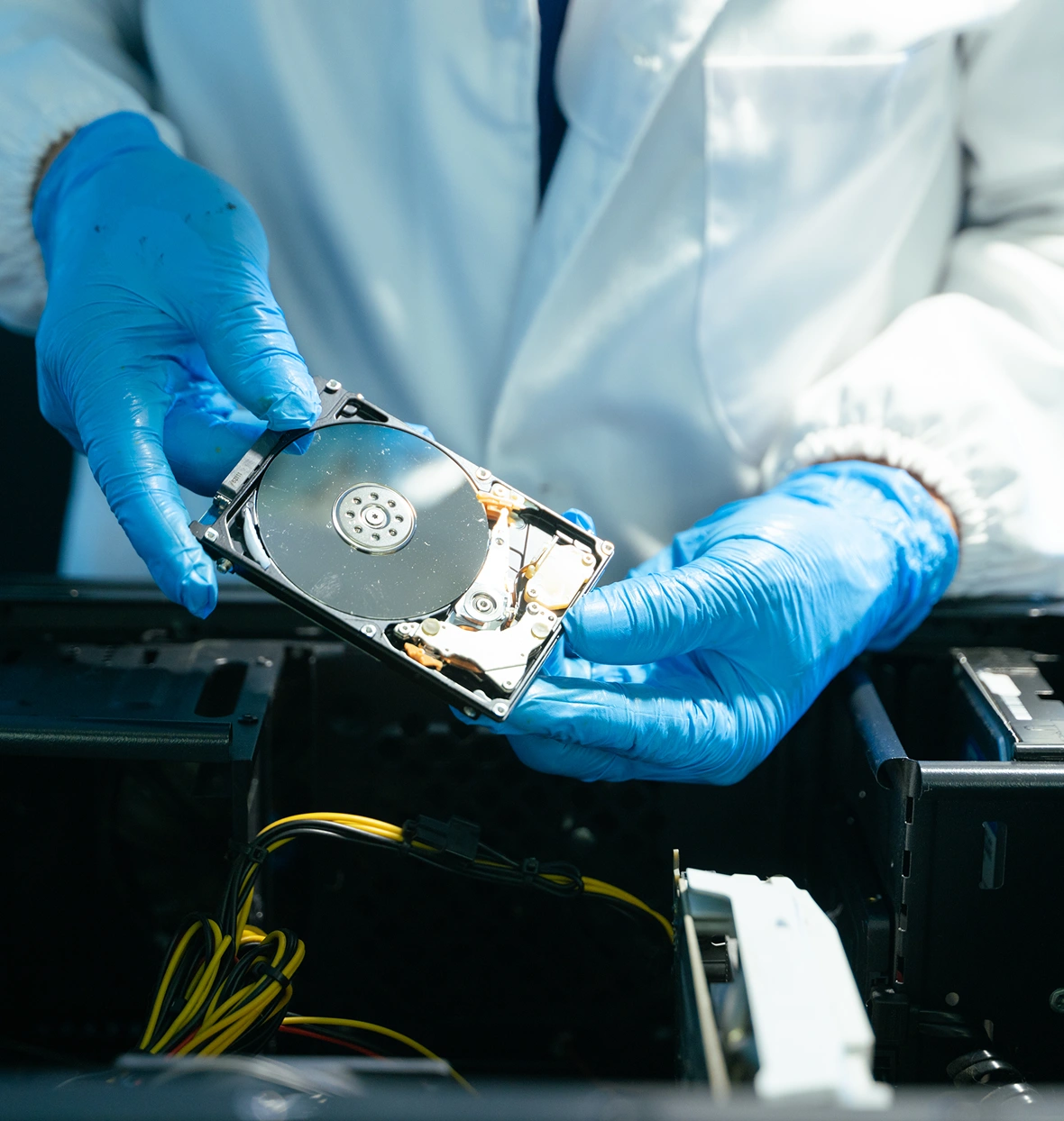 Technician handling hard drive with gloves.