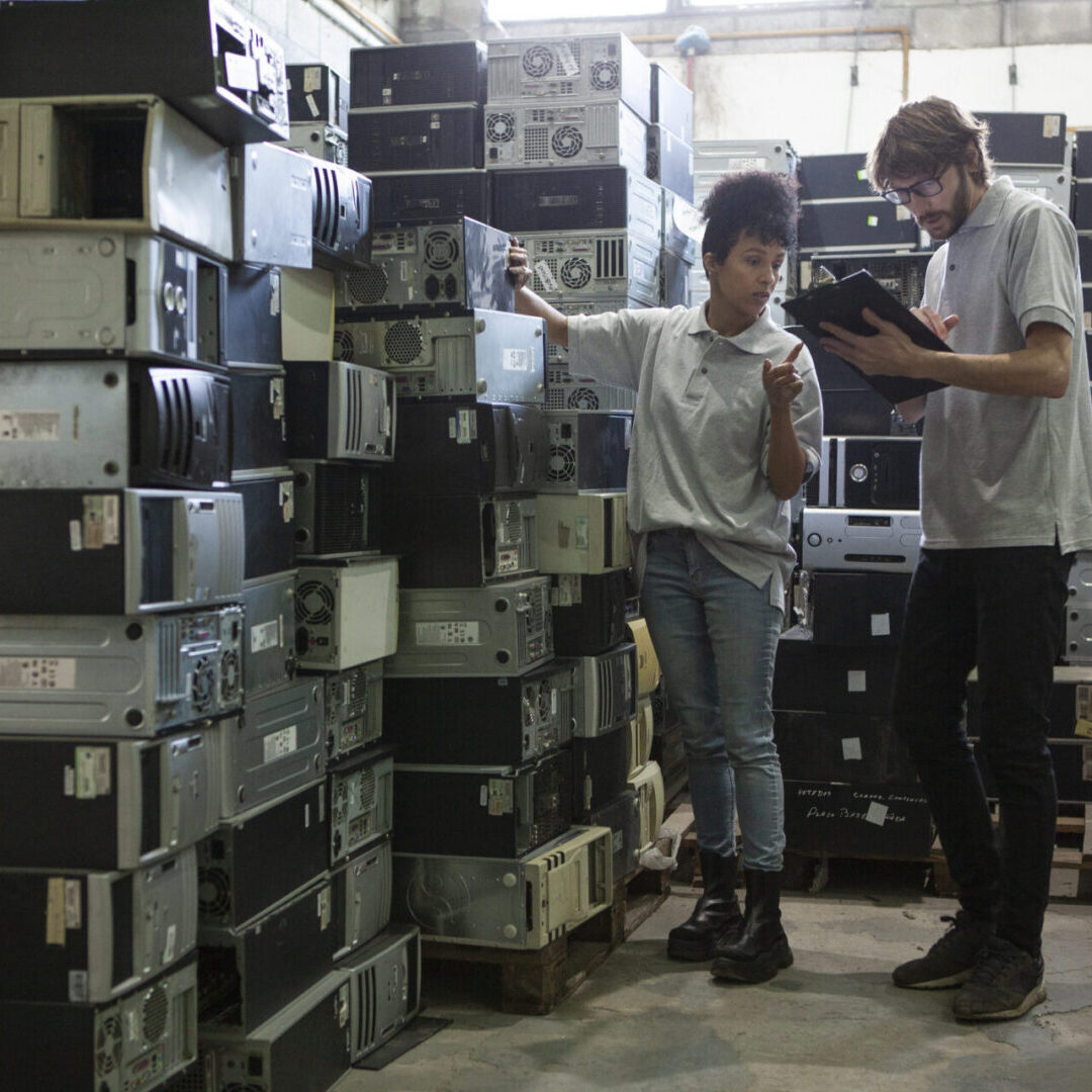 Warehouse workers sorting stacked computer units.